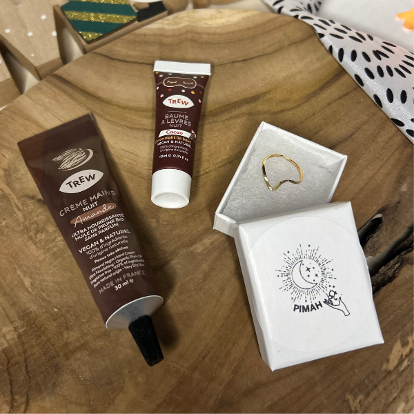 Coffret Eclat Hivernale en collaboration avec Pimah Création, ce coffret de Noël comprend : une crème mains nuit odeur Amande, un baume à lèvres nuit odeur Cacao et une bague en acier inoxydable