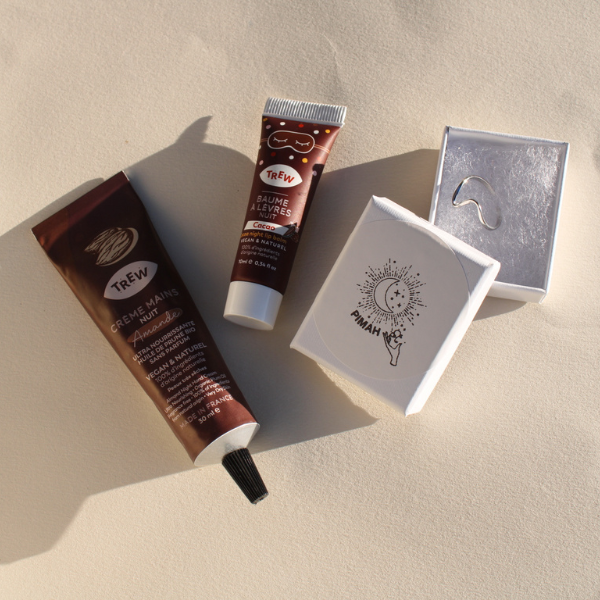 Coffret Eclat Hivernale en collaboration avec Pimah Création, ce coffret de Noël comprend : une crème mains nuit odeur Amande, un baume à lèvres nuit odeur Cacao et une bague en acier inoxydable